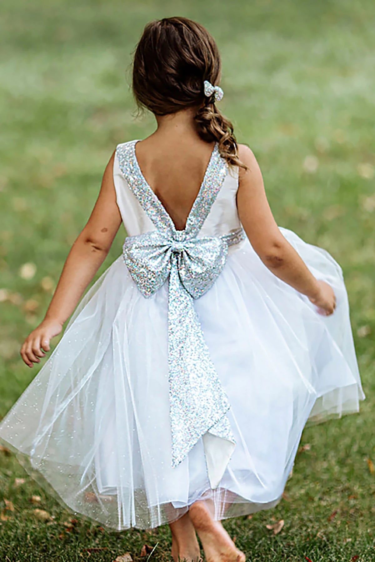 A white flower girl dress with a large bow.