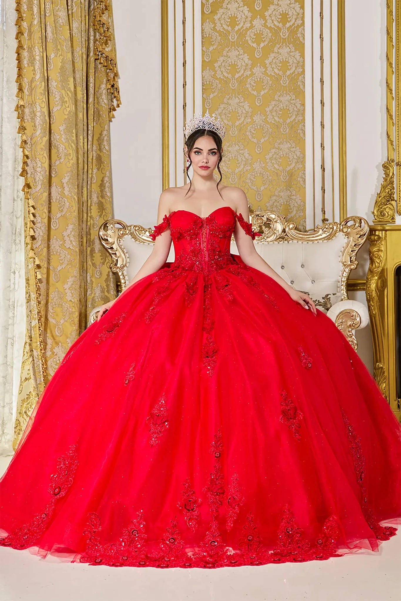 Woman standing front-facing in red quinceañera ball gown with off-shoulder floral appliqué sleeves, sheer corset bodice, and shimmering embroidered skirt