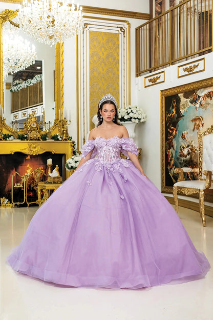 Woman standing front-facing in lilac quinceañera ball gown with off-shoulder sleeves, sheer corset bodice, floral 3D appliqués, and voluminous glitter tulle skirt