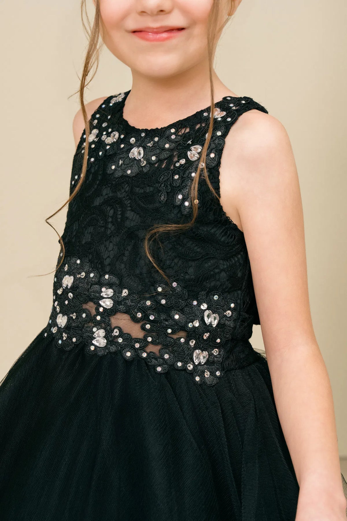 Detailed by beaded floral lace on the bodice, the Black kids party dress reveals its construction.