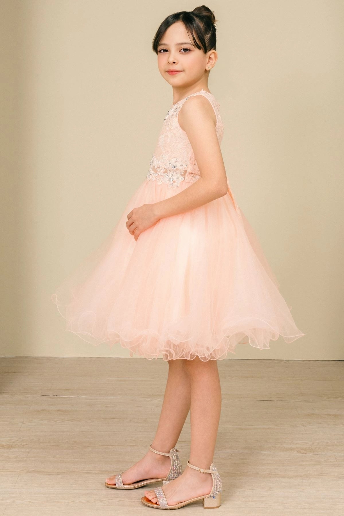 Finished details of a lace back and satin bow distinguish the Peach kids party dress.