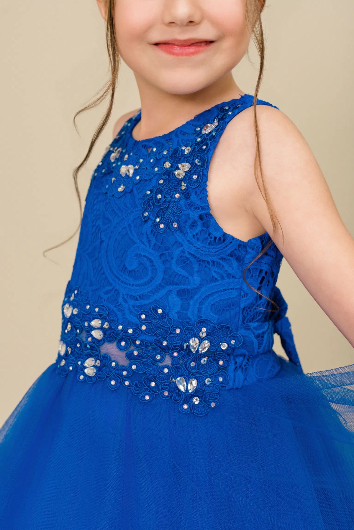 Detailed by beaded floral lace on the bodice, the Royal Blue kids party dress reveals its construction.