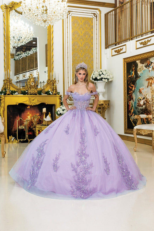 Woman standing front-facing in lilac quinceañera ball gown with off-shoulder design, intricate floral appliqués, embroidered corset bodice, and sparkling voluminous skirt