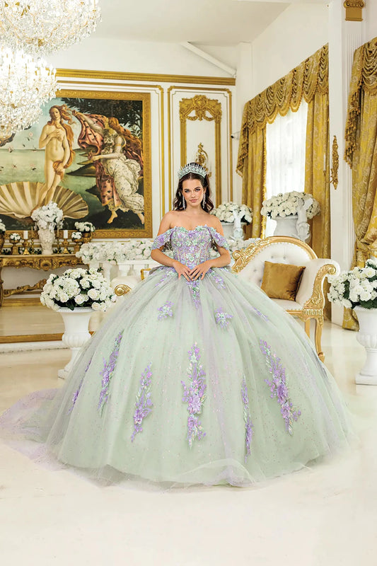 Woman standing front-facing in lilac-sage quinceañera ball gown with off-shoulder floral appliqués, corset bodice, glittered tulle skirt, and layered detailing