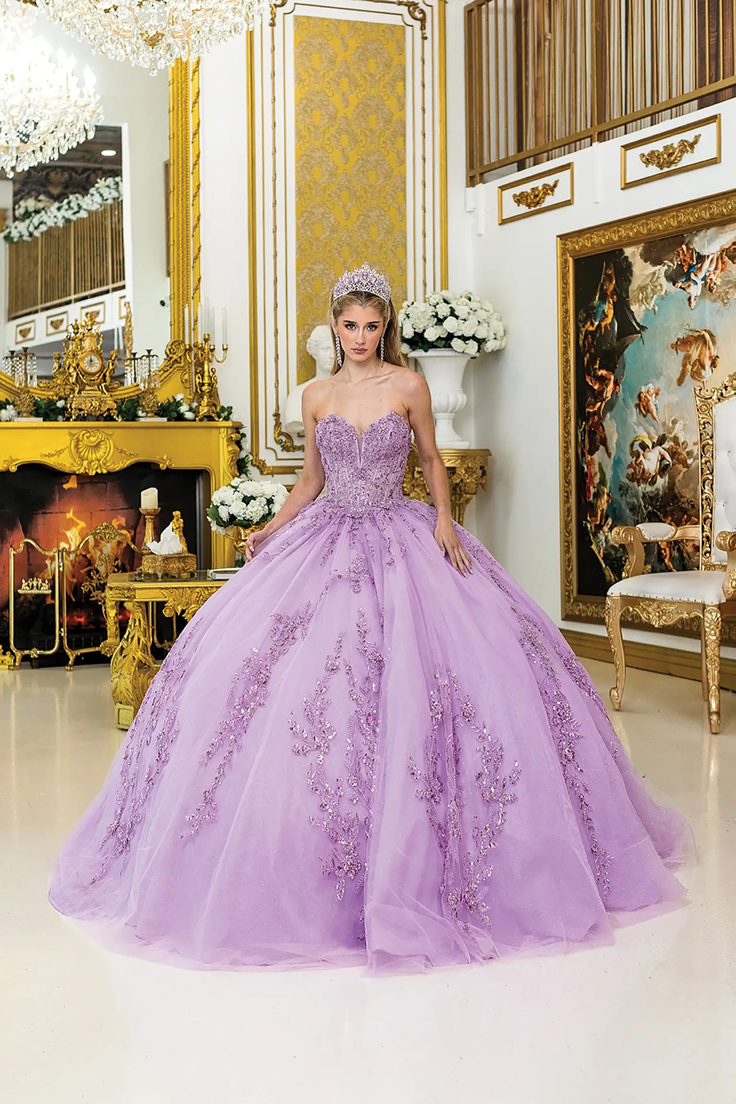 Front view of lilac quinceañera ball gown with sweetheart corset bodice, sheer structure, intricate lace appliqués, and a full tulle skirt in an ornate gold interior setting.