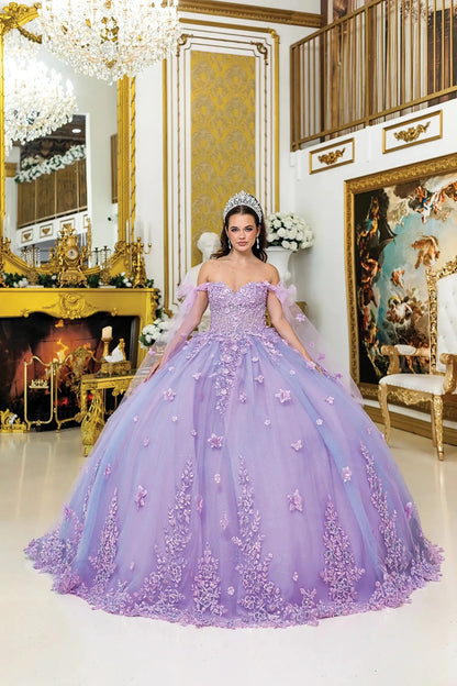 Woman standing front-facing in lilac quinceañera ball gown with off-shoulder sleeves, floral appliqués, corset bodice, and layered glitter tulle skirt