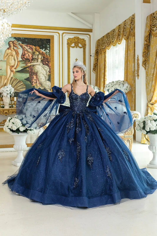 Full front view of a woman wearing a navy quinceañera dress with sweetheart neckline, sheer puff sleeves, floral appliques, corset bodice, and glitter tulle ball gown skirt