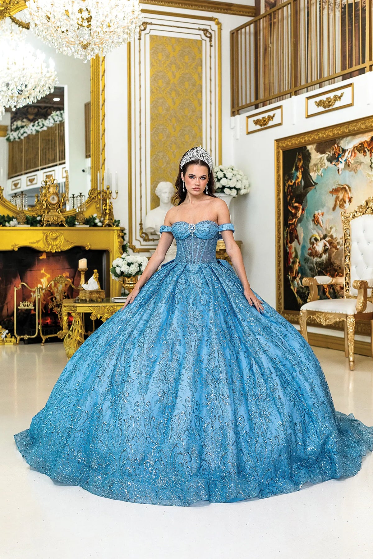 Showing intricate embroidery across its full glitter tulle skirt, this Dusty Blue quinceañera ball gown is shown in full view.