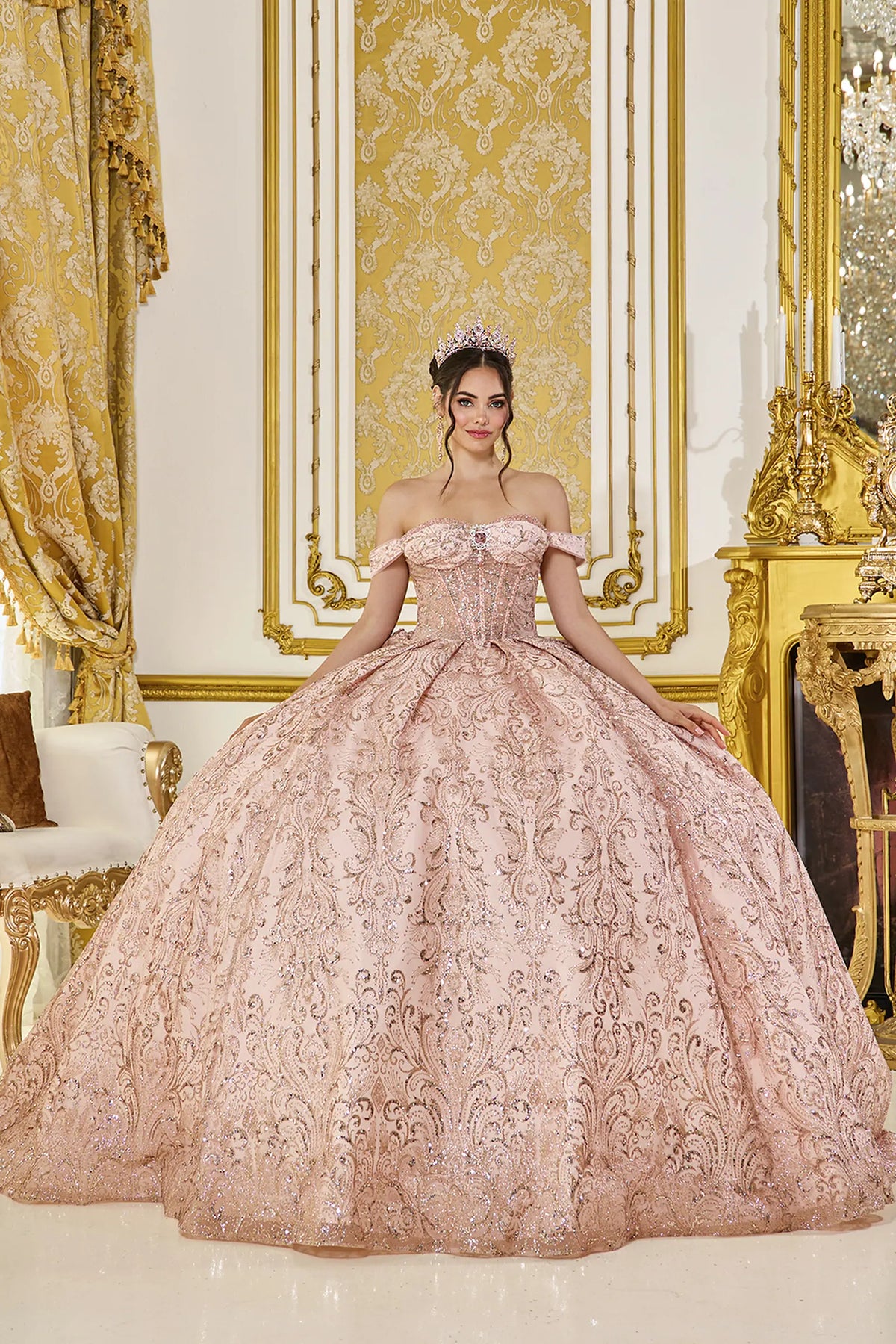 Showing intricate embroidery across its full glitter tulle skirt, this Rose Gold quinceañera ball gown is shown in full view.