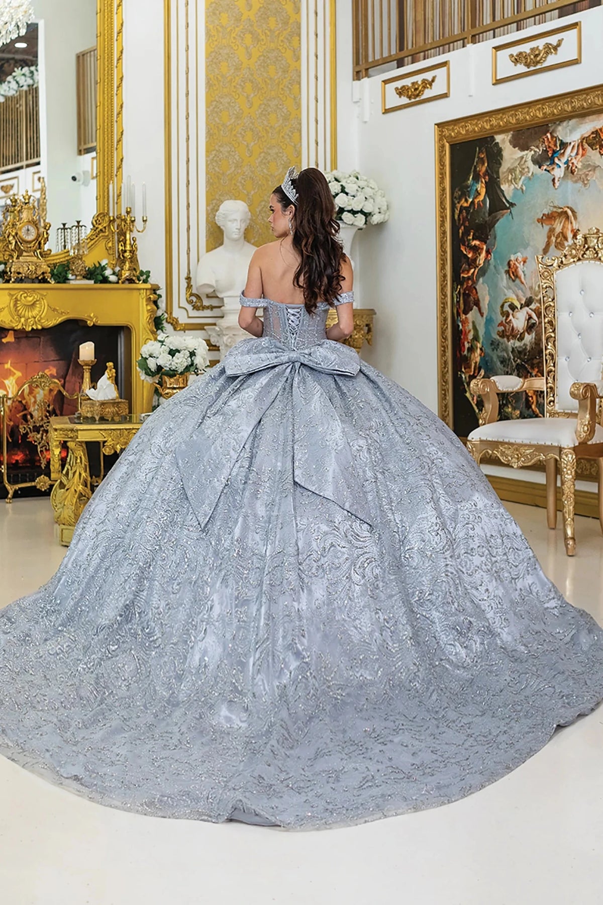  voluminous light silver ball gown with a large bow at the back and a long train. 