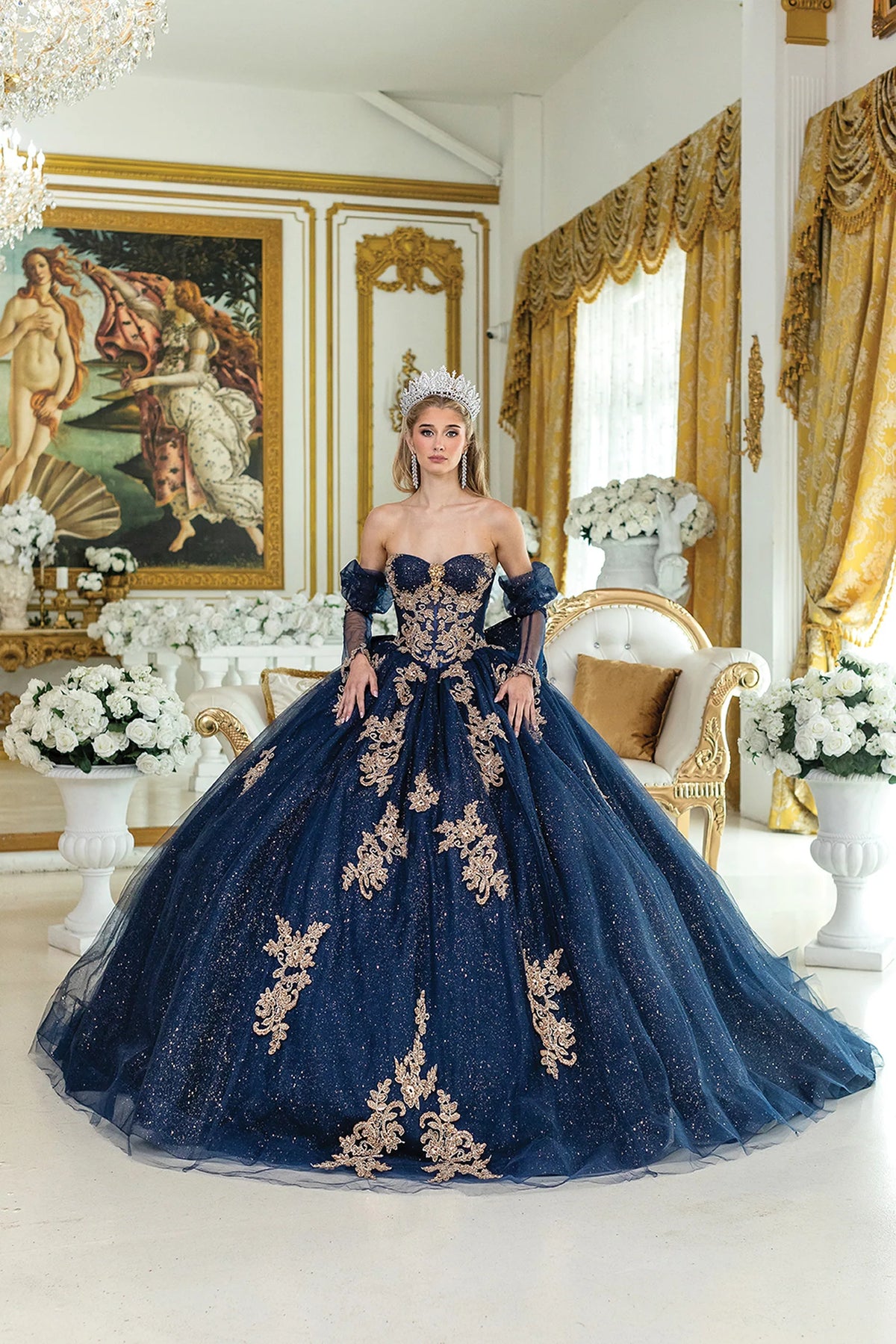 Showing embroidered appliqués across its sweetheart bodice and skirt, this Navy quinceañera ball gown is shown in full view.