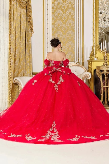 Back view of red quinceañera ball gown featuring a lace-up corset back, oversized bow accent, and long flowing glitter tulle train with gold applique detailing