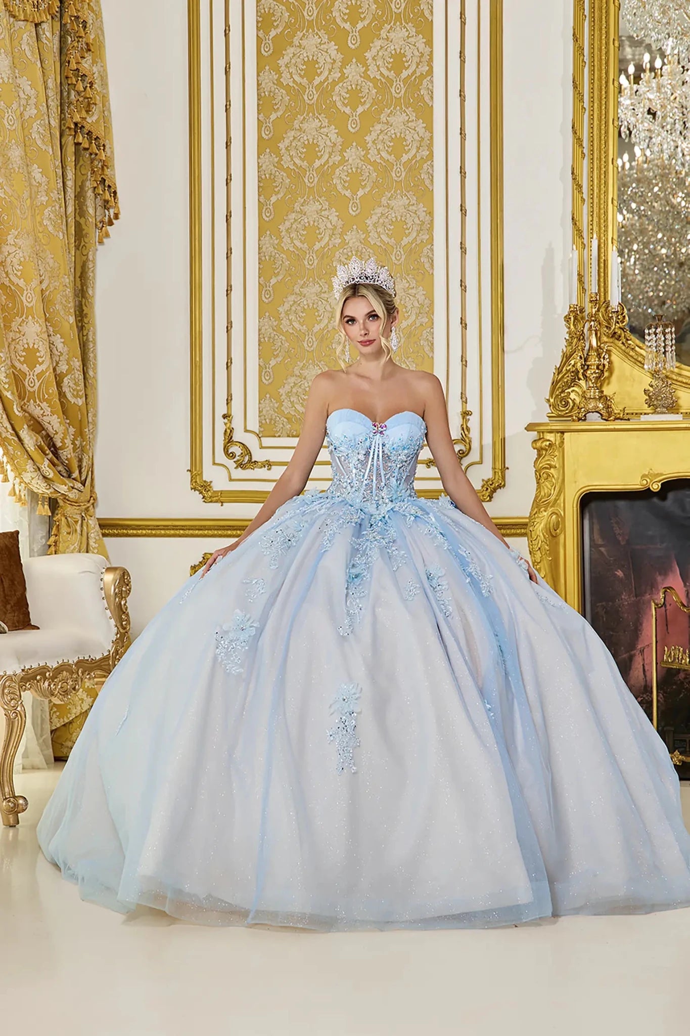 Front view: Light blue quinceañera ball gown with sweetheart corset bodice, crystal embellishments, lace appliqués, and a full glitter tulle skirt in an elegant palace setting