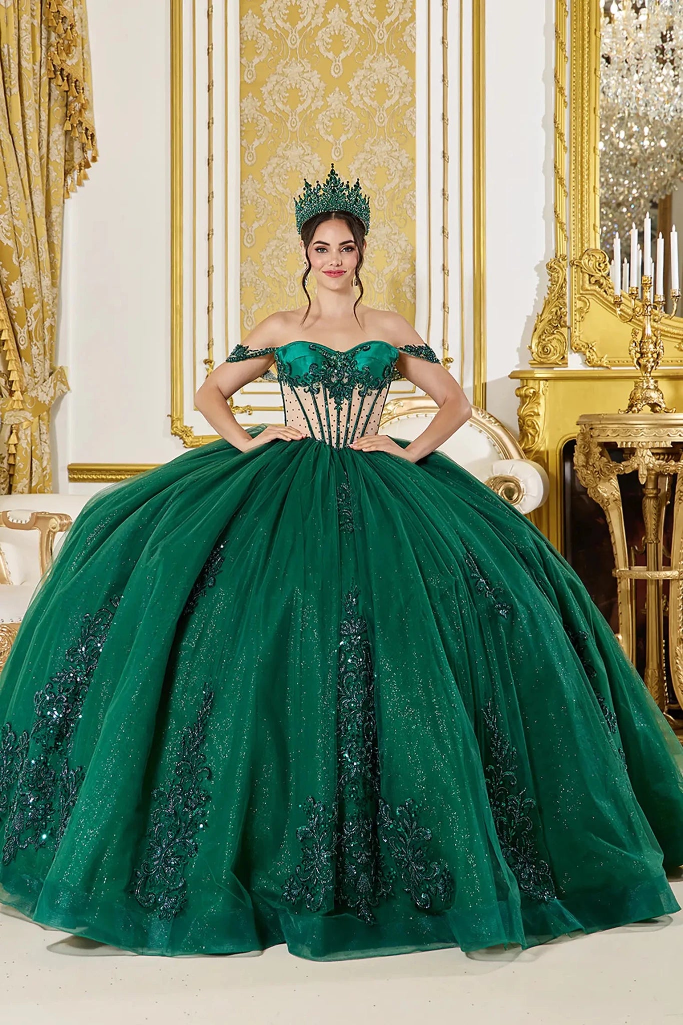 Front view: Emerald green quinceañera ball gown with off-the-shoulder corset bodice, sheer boning details, lace appliqués, and a full glitter tulle skirt in a regal palace setting
