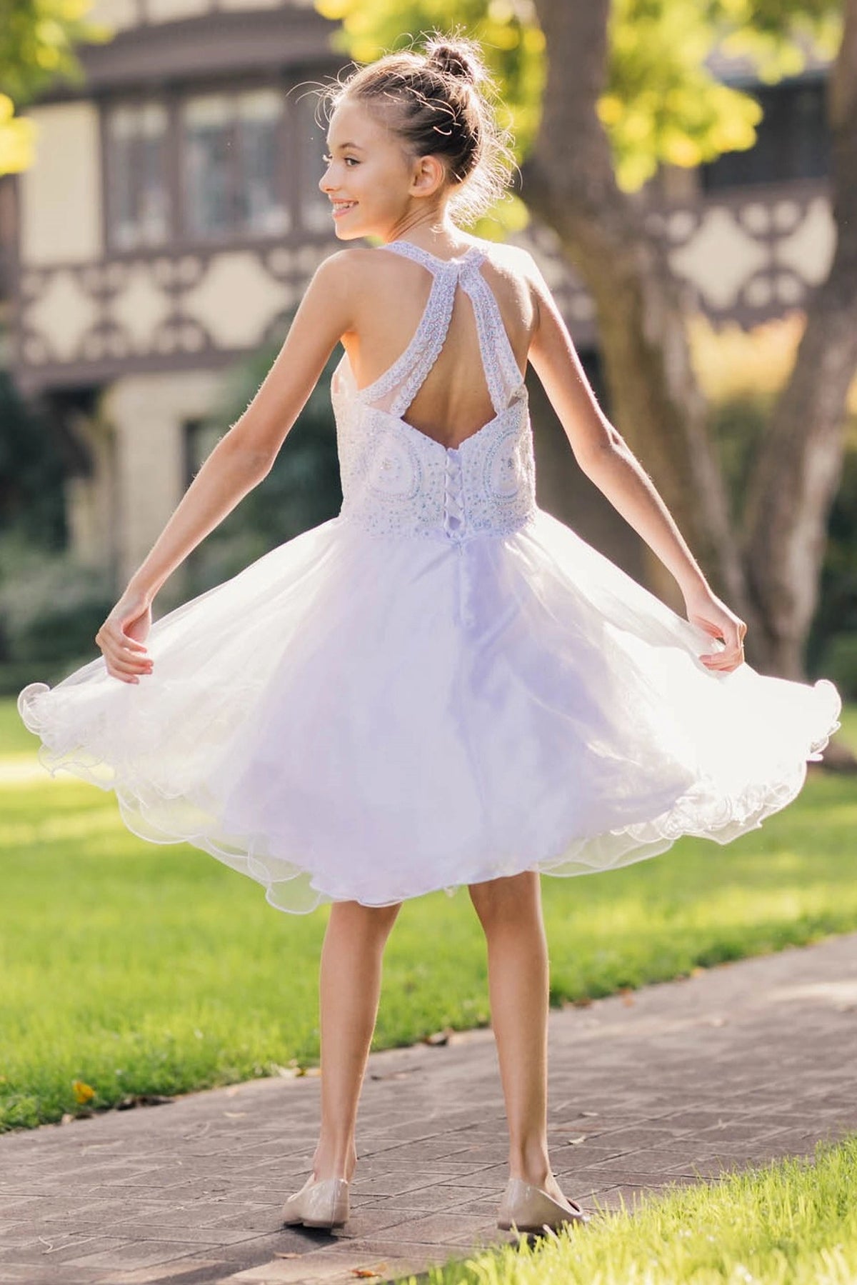 Detailed by crossed halter straps, the White kids party dress reveals its construction.