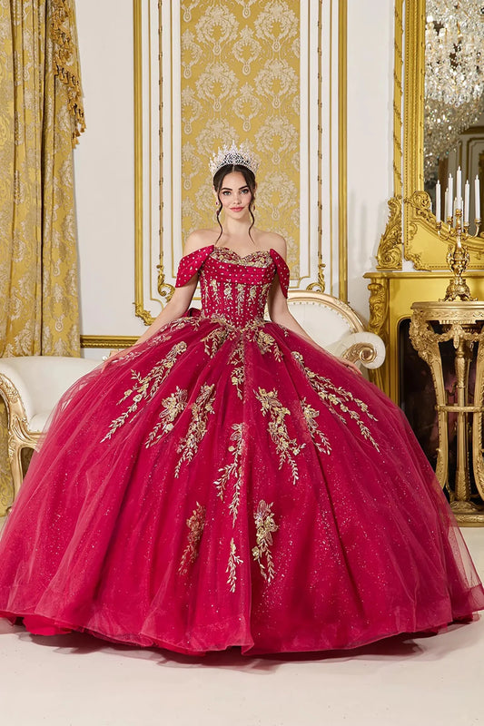 Woman wearing burgundy off-shoulder sweetheart quinceañera dress with gold embroidered corset bodice, draped satin straps, metallic appliqué, and glitter tulle full skirt