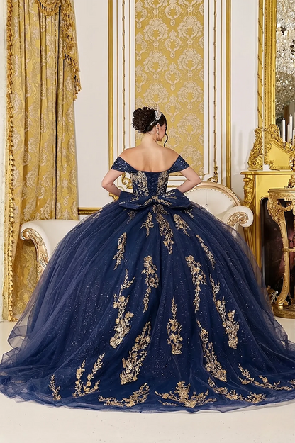 Woman back-facing in navy quinceañera dress with  gold embroidery, metallic appliqué, and cascading glitter tulle skirt