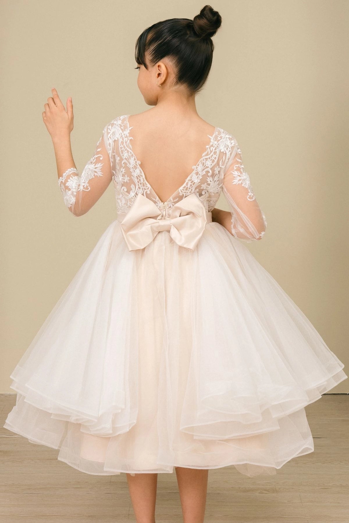 Finished details of a V-shaped lace back and large bow distinguish the Champagne kids party dress.