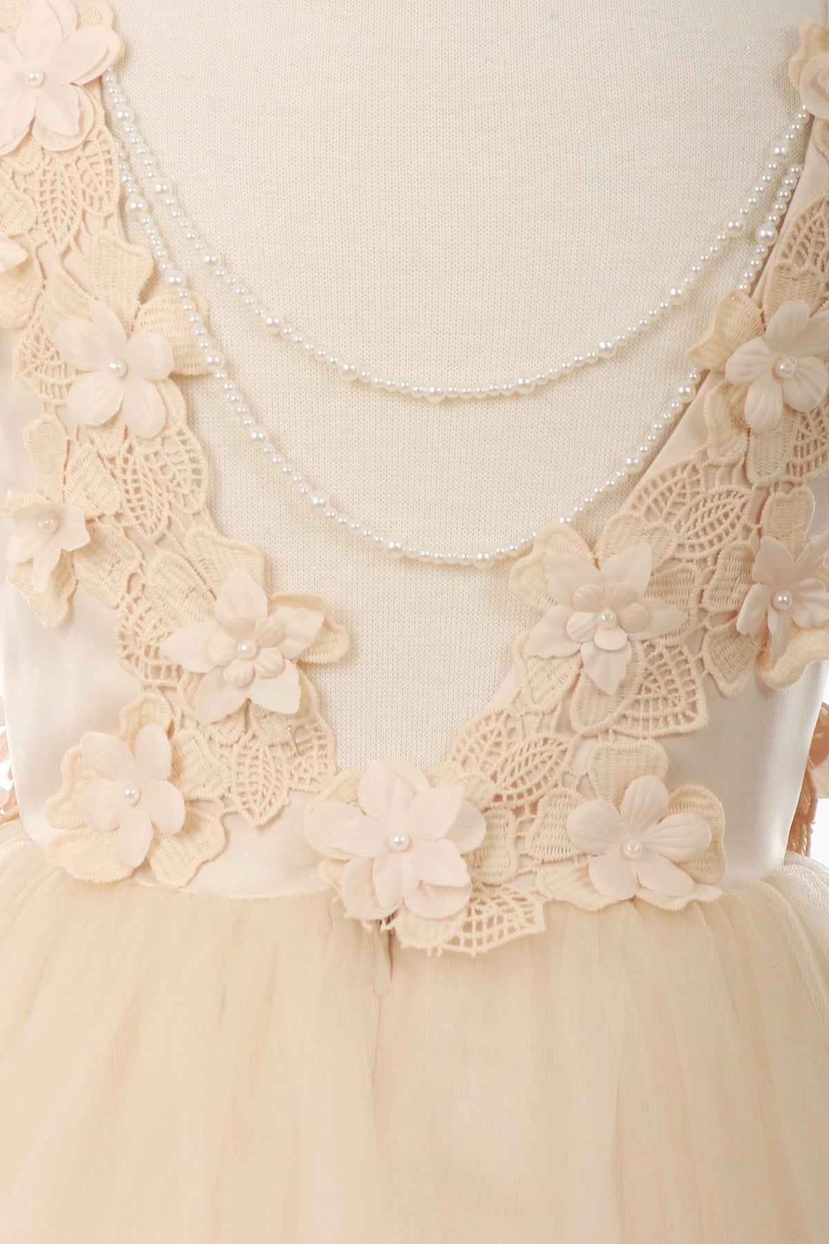 Detailed by dimensional flower appliques on the bodice, the Champagne kids party dress reveals its construction.