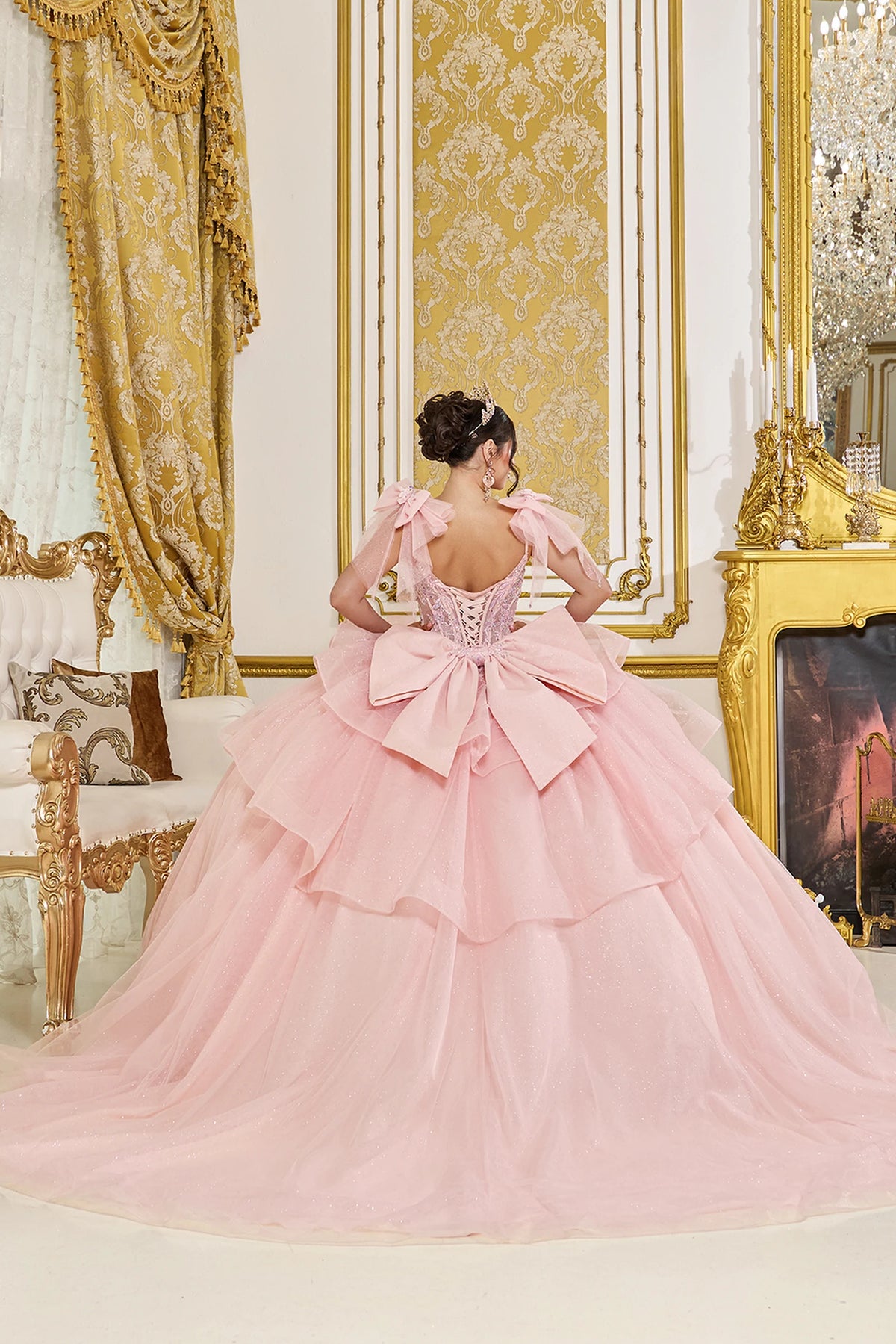 Back view of a Blush quinceañera gown showing lace-up back, detachable puff sleeves, and ruffled layered skirt