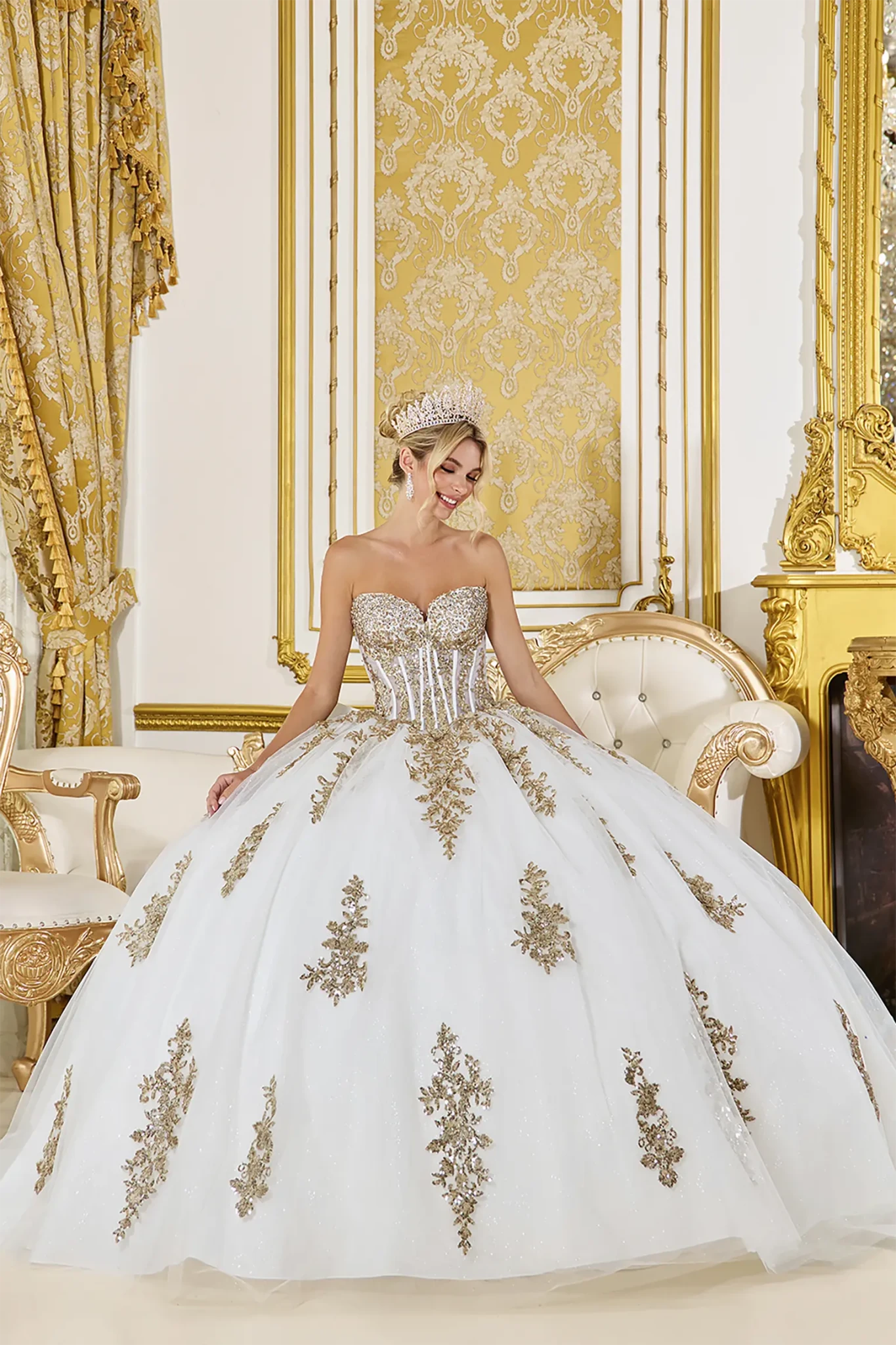Front view of a woman wearing off-white quinceañera dress with strapless beaded corset, gold embroidery and glitter tulle skirt