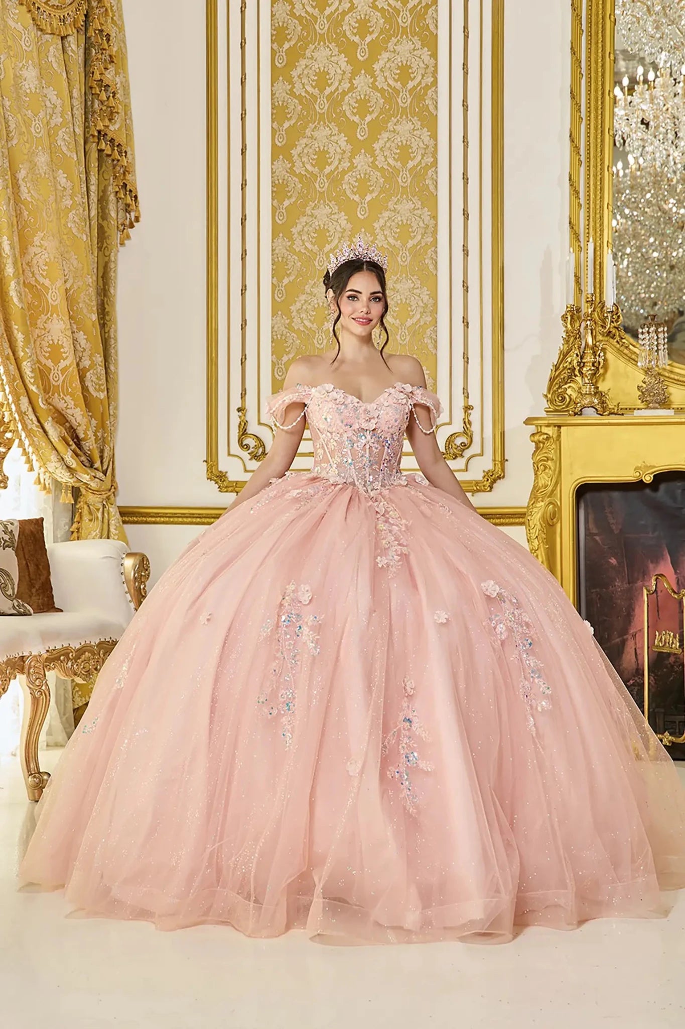 Woman in a peach pink quince ball gown standing in an opulent room with gold decor.
