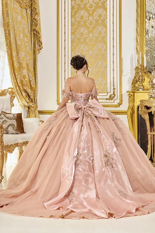Back view of rose gold quinceañera ball gown featuring a lace-up corset back, oversized satin bow, and long flowing train with delicate applique details