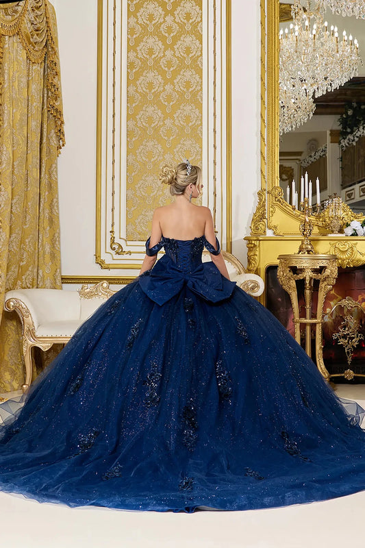 Back view of navy blue quinceañera ball gown featuring a lace-up corset back, structured bow accent, and long flowing glitter tulle train with embroidered details