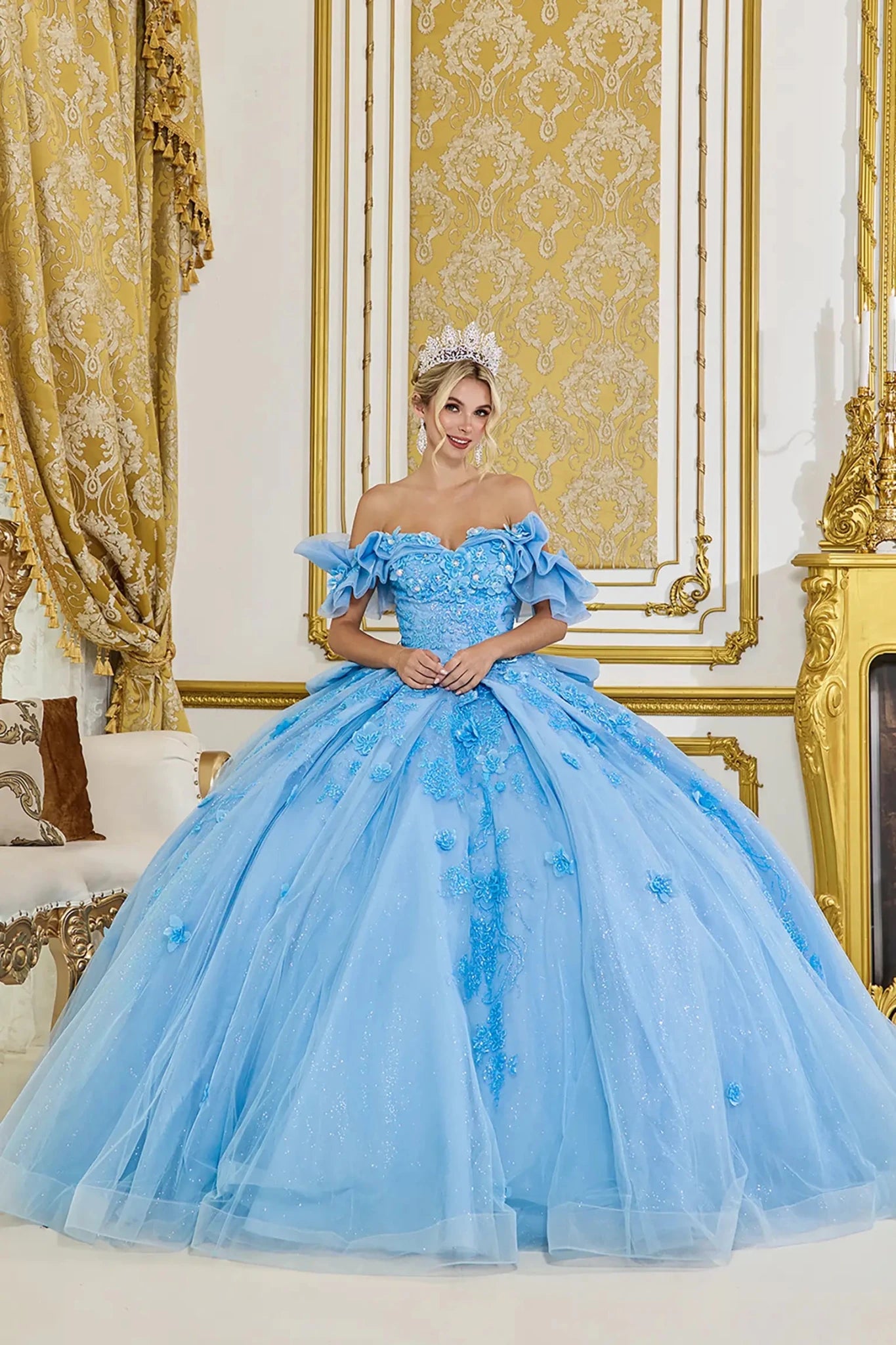 Woman standing front-facing in elegant Bahama blue ball gown with 3D floral appliqué bodice, ruffle sleeves, and voluminous layered skirt