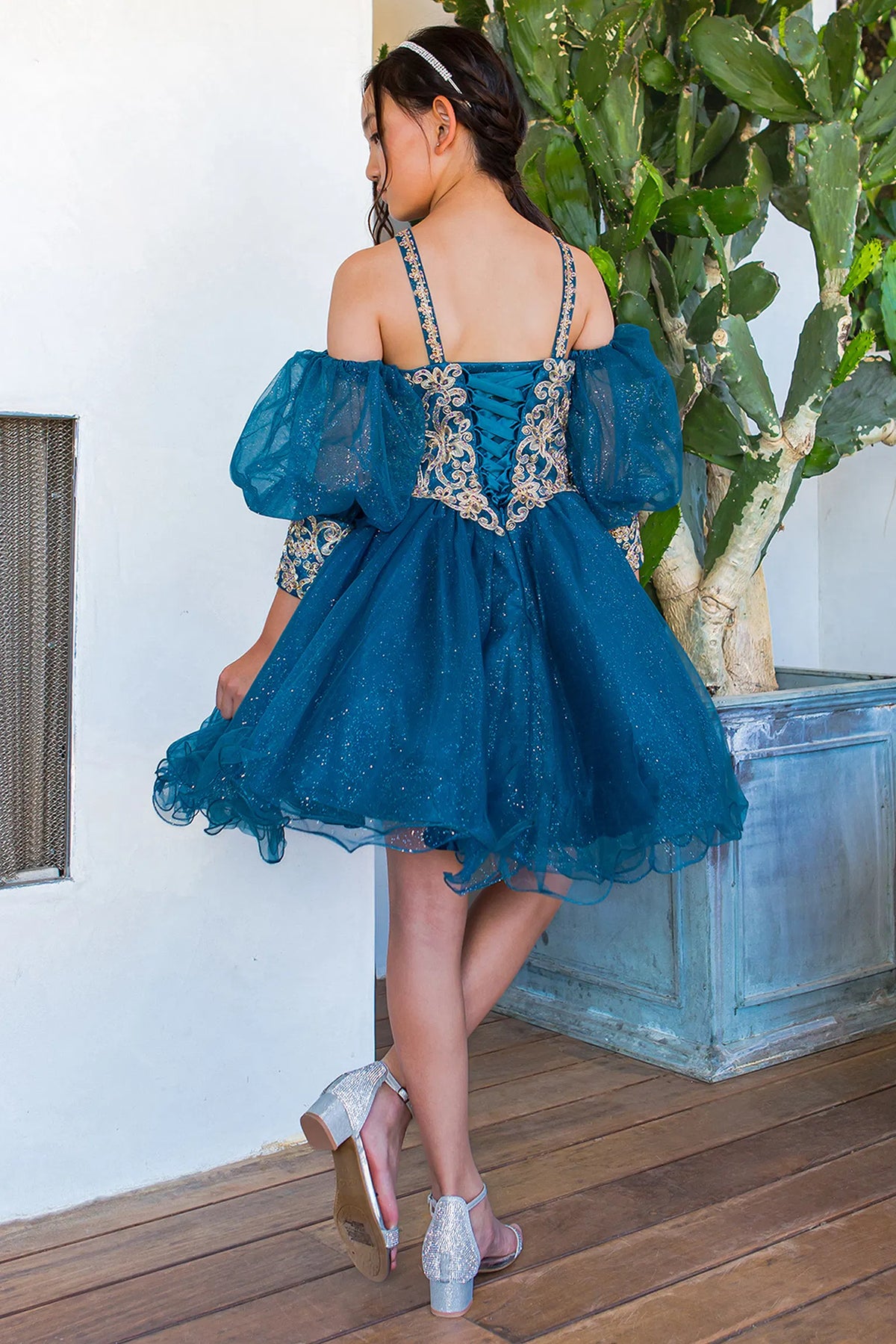 Lace-up ribbons close the gold-trimmed back of this Peacock kids party dress.
