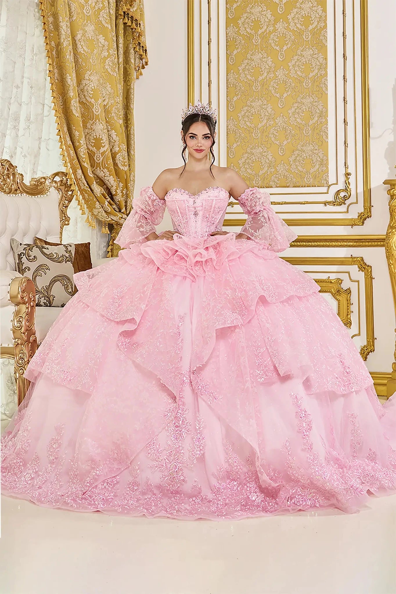 Front view of pink quinceañera ball gown with off-the-shoulder puff sleeves, sweetheart corset bodice, and layered glitter tulle skirt with ruffle details.