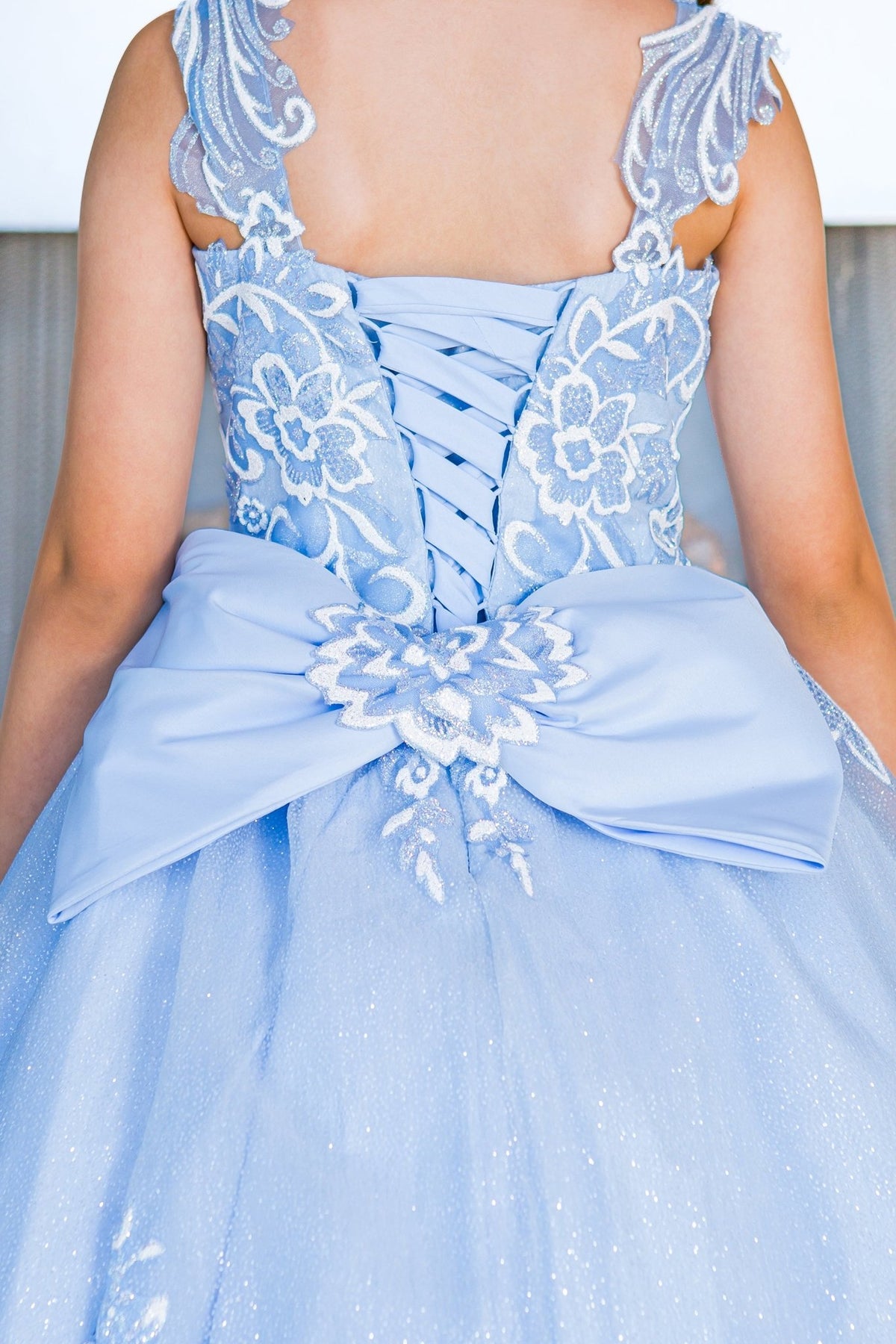 Close-up back view of blue mini quince dress with sparkling fabric 3D flower puff print and detachable back ribbon