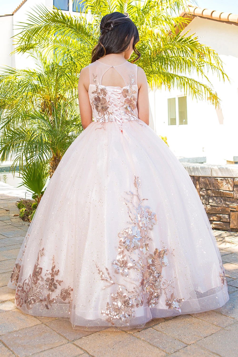 Displayed in a back view, the Blush mini quince dress has lace-up back and floral appliques across the tulle skirt.