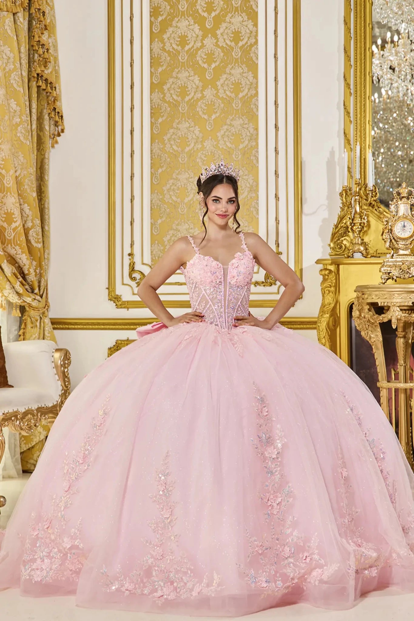 Woman in a pink ball gown standing in an opulent room with gold decor.