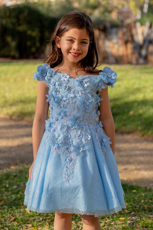 Young girl standing front-facing in blue off-the-shoulder flower girl dress with 3D floral appliqué bodice and shiny layered tulle skirt
