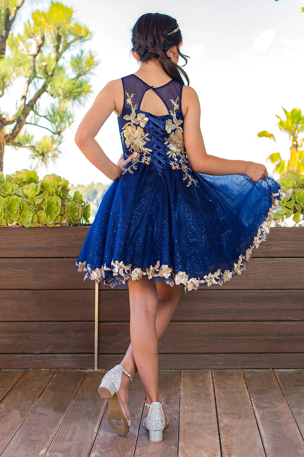 Detailed by a lace-decorated back bodice, the Navy kids party dress reveals its construction.