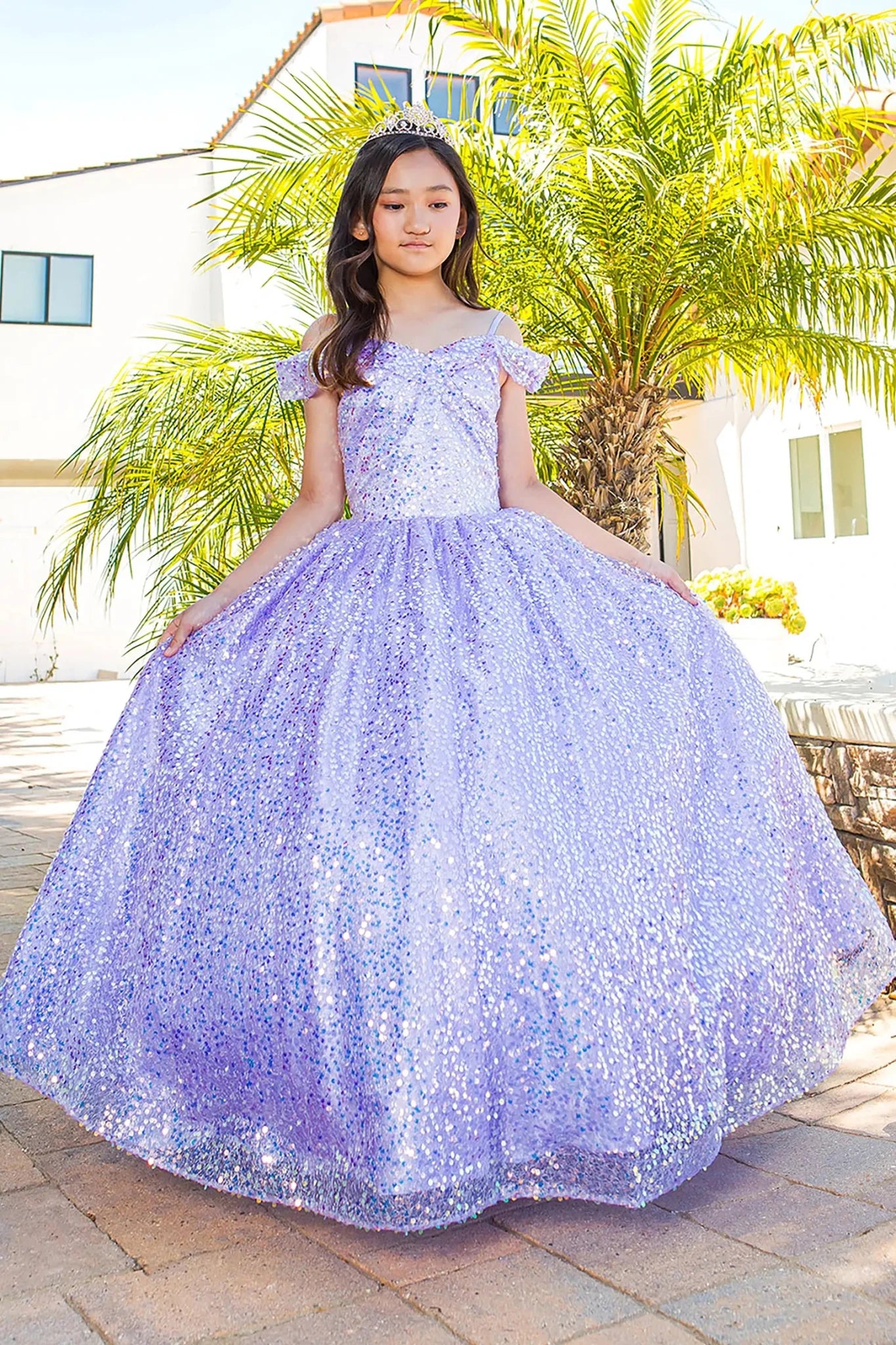 Girl standing front-facing in lilac mini quinceañera dress with sparkling fabric, delicate 3D flower puff print, fitted bodice, and elegant A-line skirt