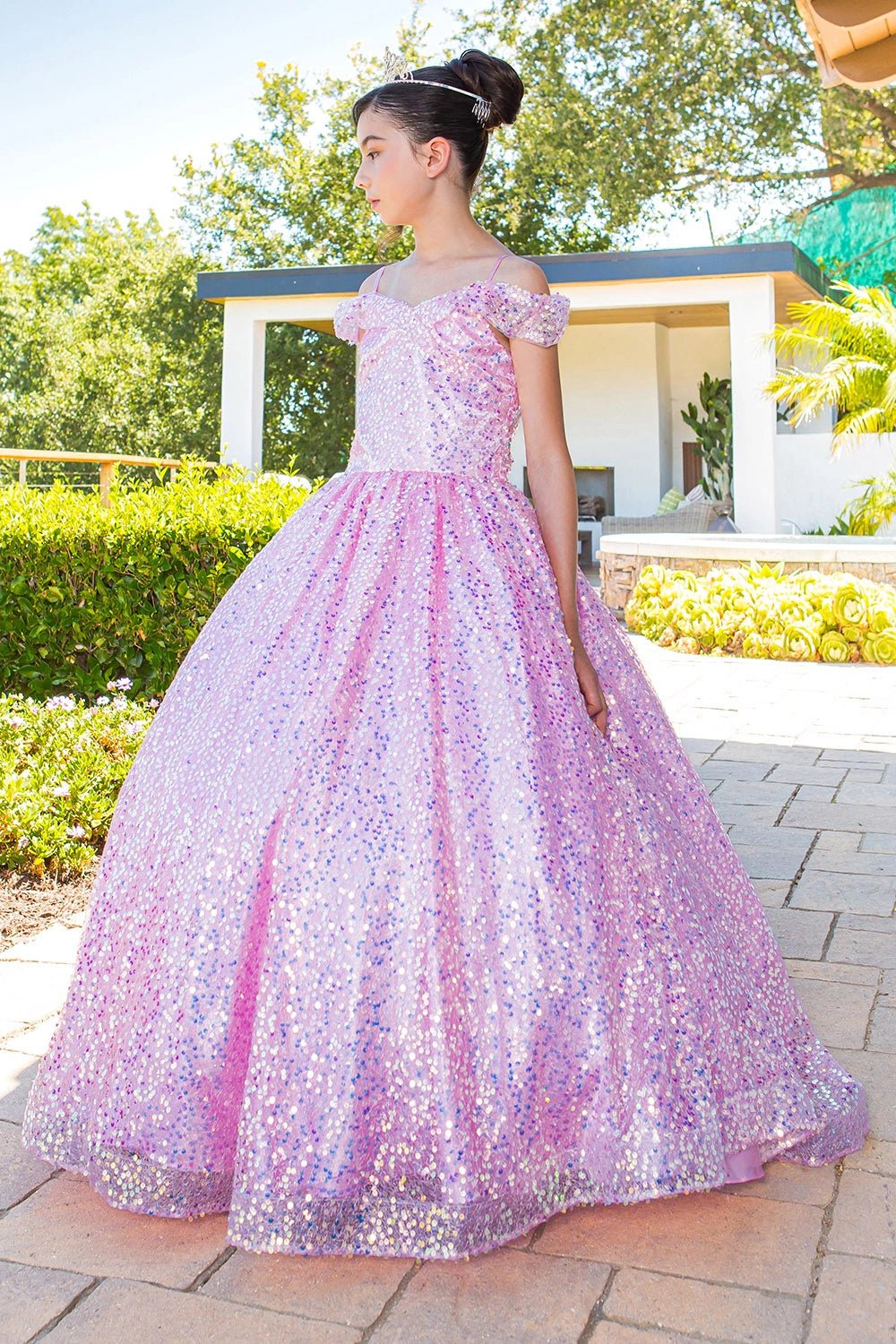 Shown in a angled view, the Pink mini quince dress has off-shoulder sequin bodice and full sparkling skirt.
