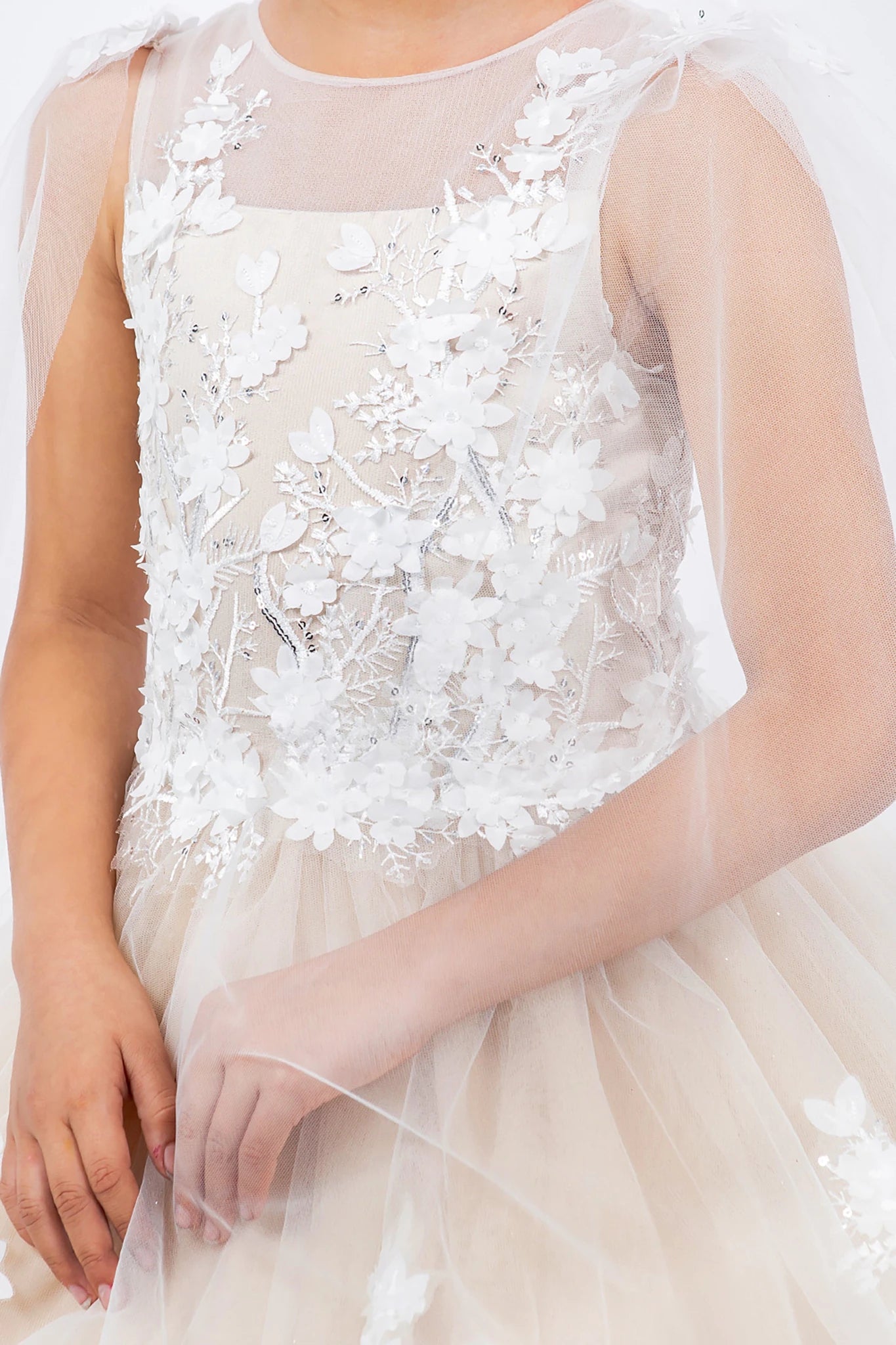 Close-up of a white lace flower girl dress with floral details. Also suitable as a mini quince dress.