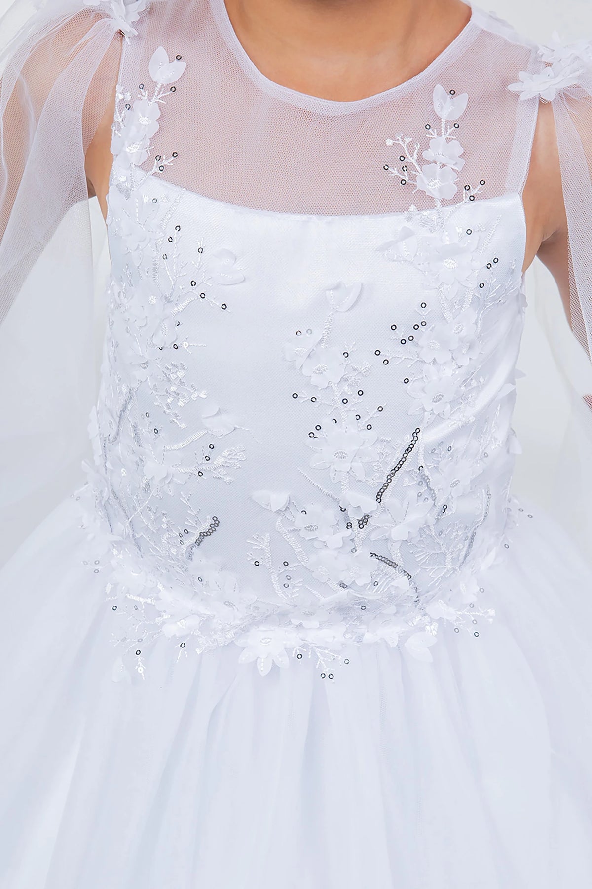 White lace flower girl dress with floral embellishments and a sheer overlay.