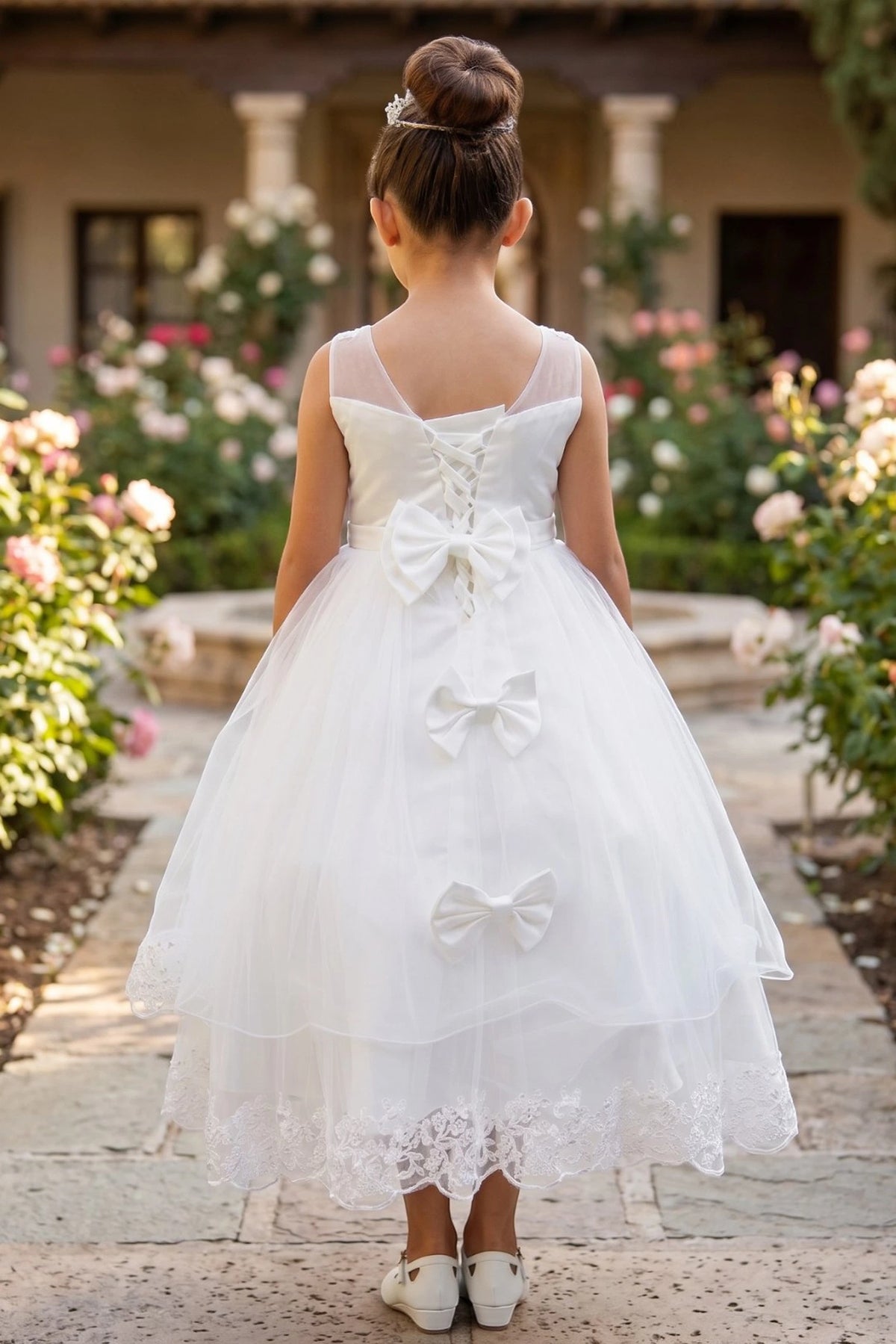 A Off-White flower girl dress showing lace-up back and two satin bows.