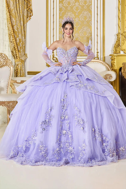Woman in a lavishly decorated room wearing an elegant purple gown with floral details.