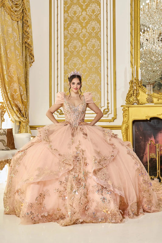 Woman standing front-facing in rose gold quinceañera ball gown with detachable cap sleeves, ornate glitter floral appliqués, fitted bodice, and voluminous ruffled tiered skirt
