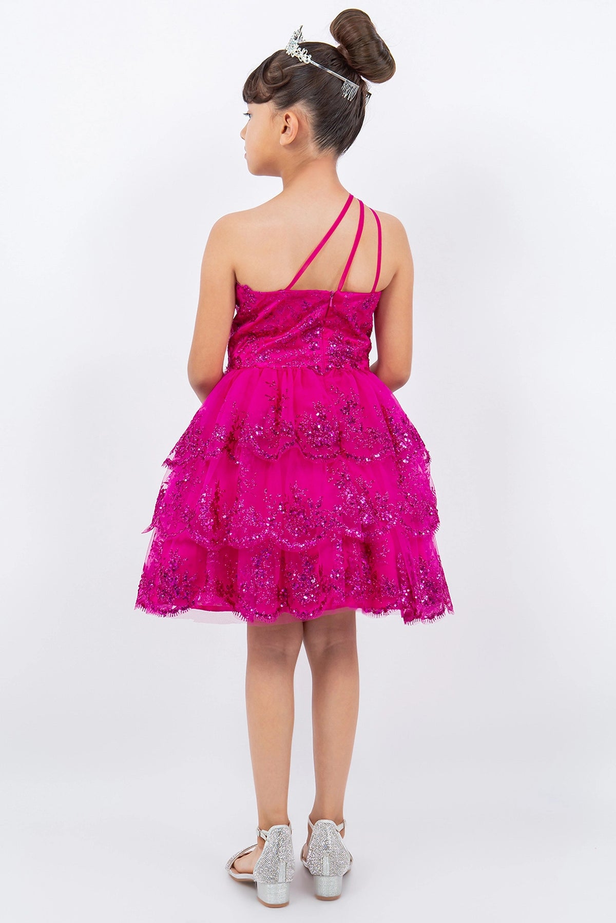 Detailed by a low back with angled straps, the Fuchsia kids party dress reveals its construction.