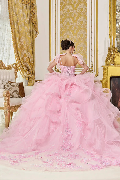 Back view of pink quinceañera ball gown featuring a lace-up corset back, dramatic ruffled tulle skirt, and long flowing train with embroidered applique accents