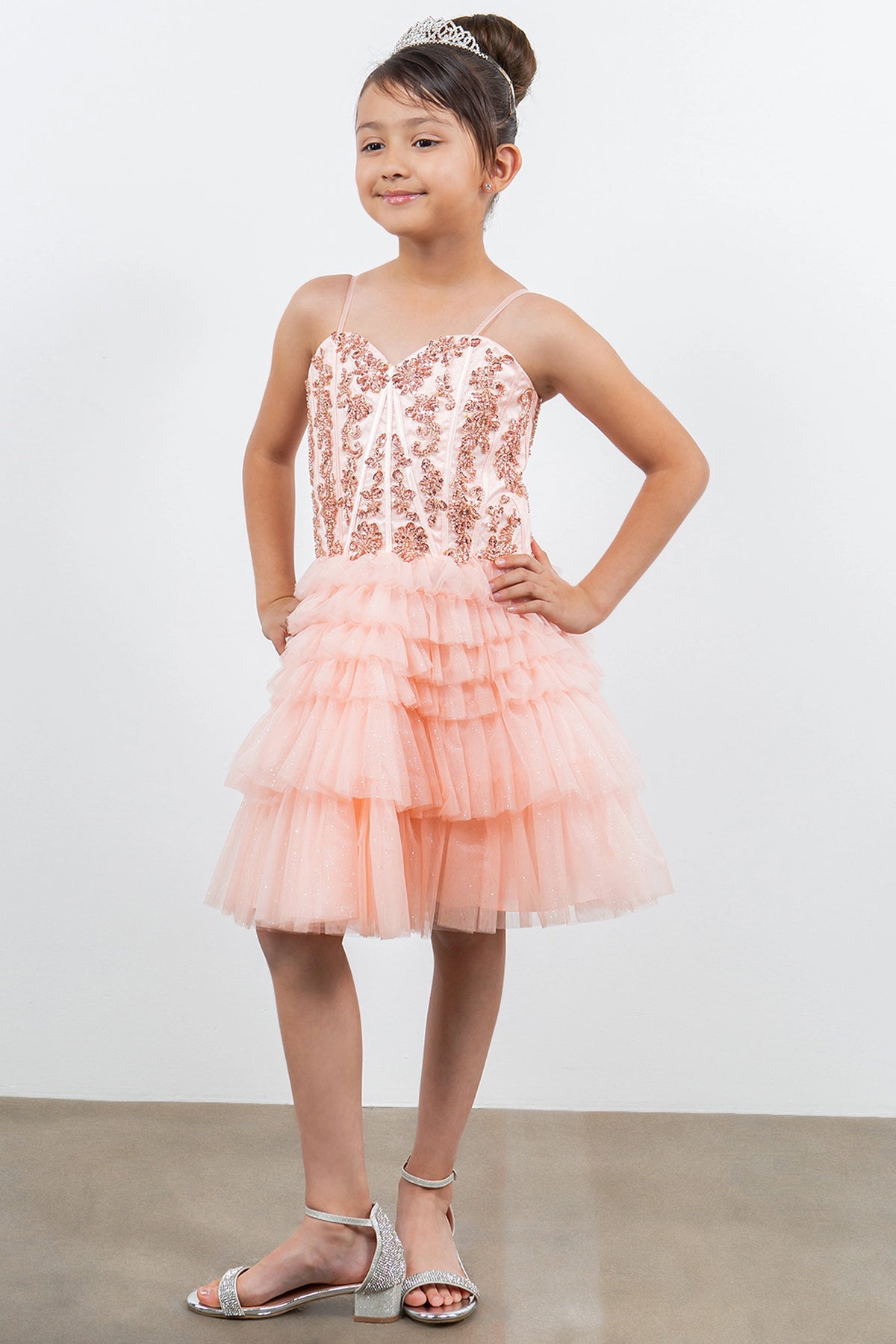 Trimmed by tiered tulle ruffles, the Blush kids party dress reveals its construction.