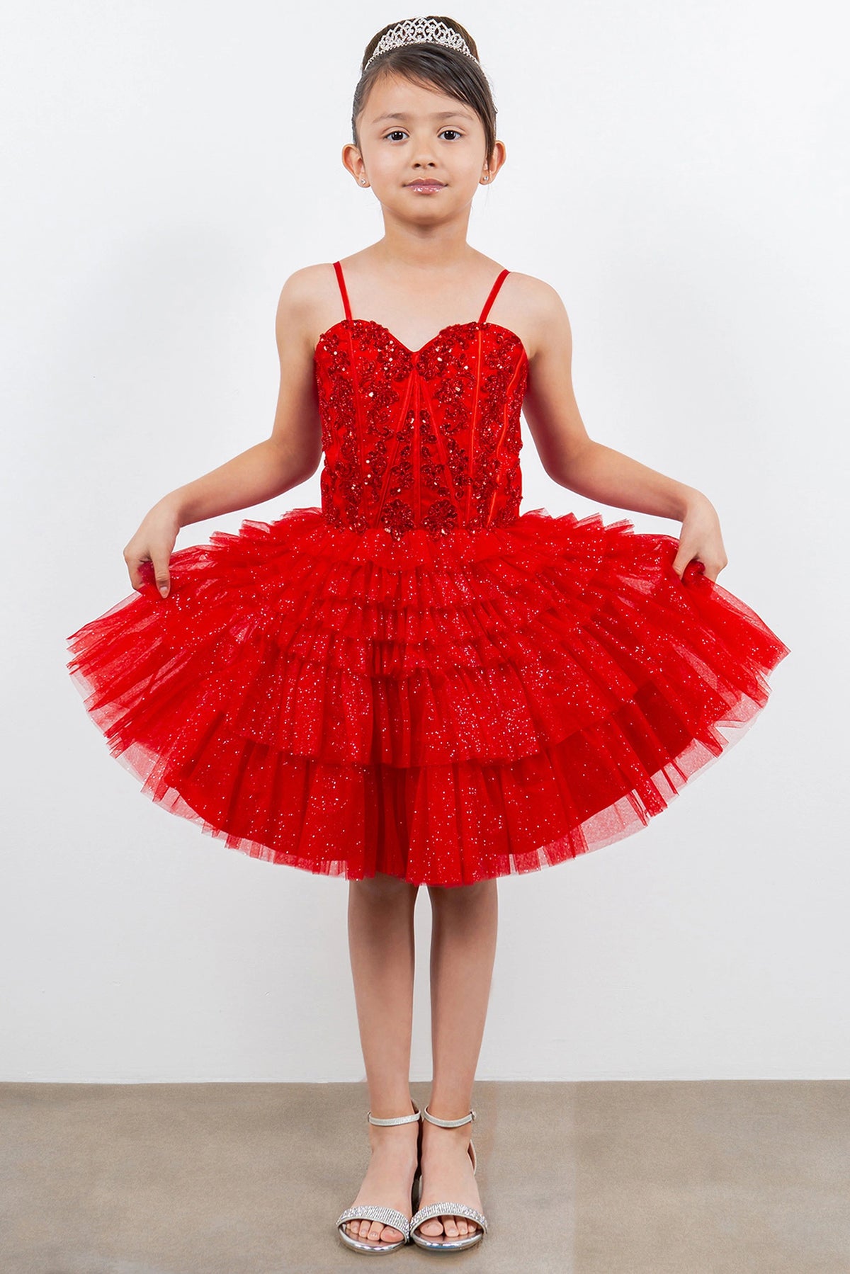 Trimmed by tiered tulle ruffles, the Red kids party dress reveals its construction.