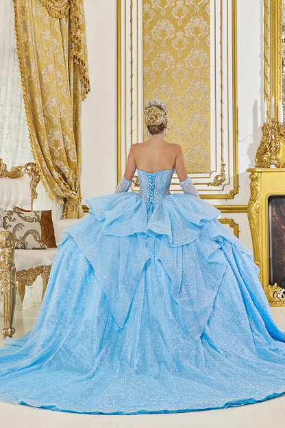Woman standing back-facing in Bahama blue ball gown with lace-up bodice, dramatic overskirt cascade, and gloves