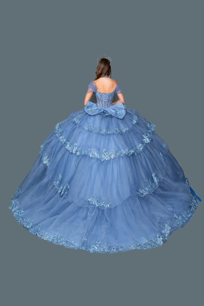 Back view of smoky blue quinceañera ball gown featuring a lace-up corset back, oversized bow detail, and tiered tulle skirt with embroidered trim on a clean background