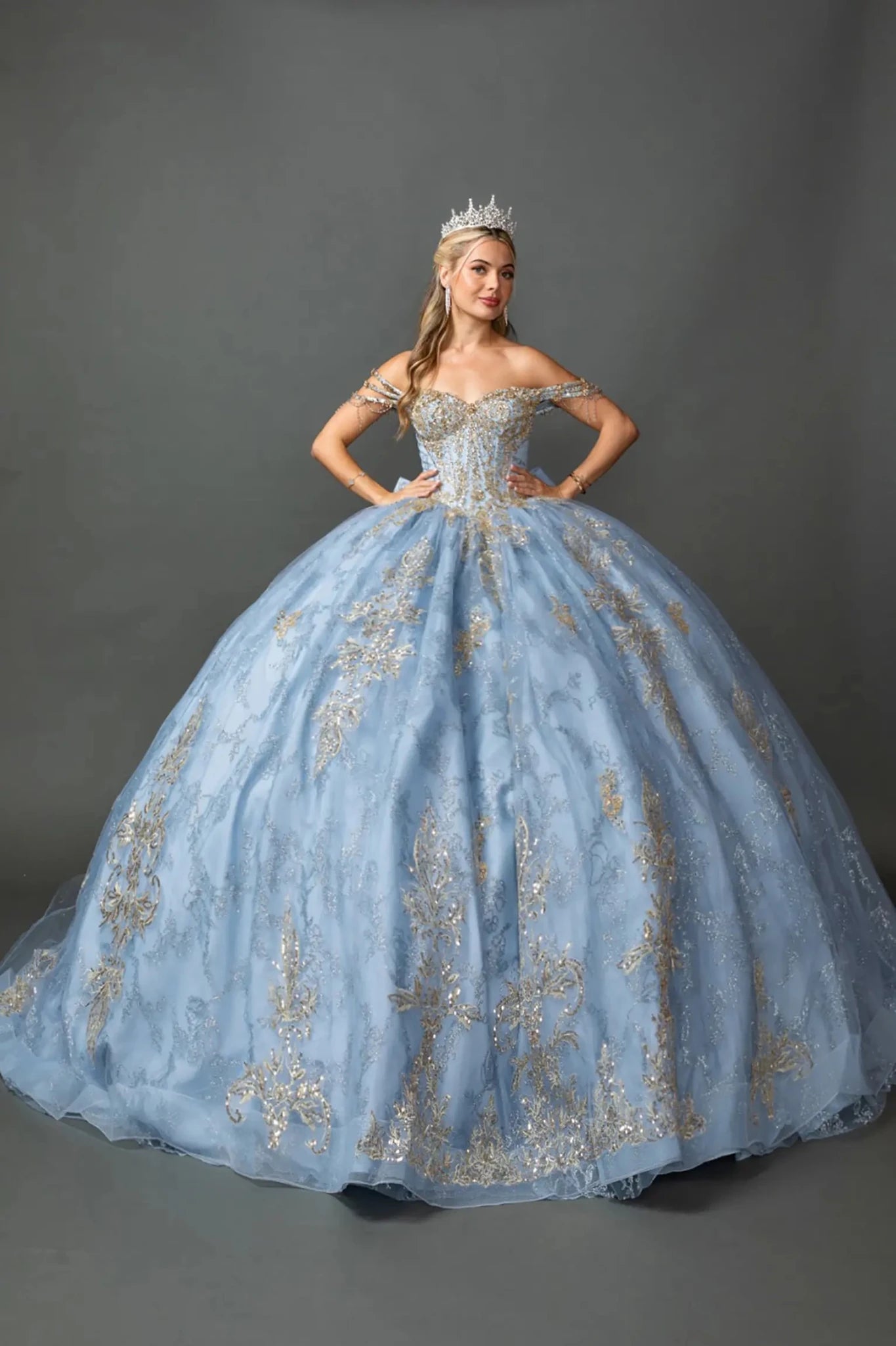 Front view of a woman wearing dusty blue quinceañera, off-shoulder, metallic embroidery, beaded and glitter tulle skirt